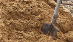 Construction shovel stuck in the sand.