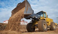 Wheel loader machine unloading sand at eathmoving works in construction site